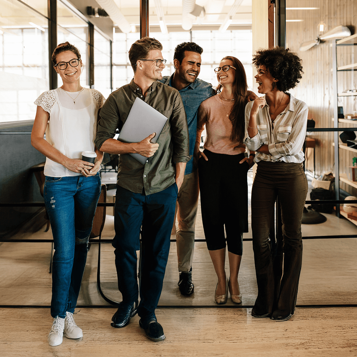 Group of four professionals smiling and walking in a modern office, representing coaching teams using an LMS platform.