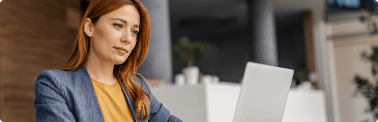 Woman working on a laptop at a desk.
