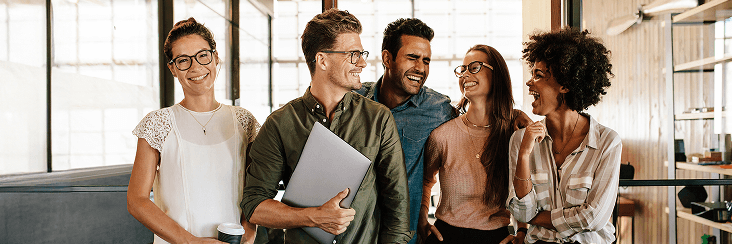 Group of people collaborating indoors, smiling and talking.