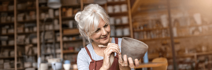 Older woman smiling while working in a workshop or studio.