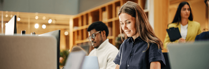 Professional at a laptop in a bright office setting.